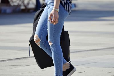 Low section of woman standing on footpath in city