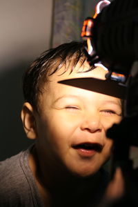 Close-up of boy with eyes closed in front of illuminated light at home