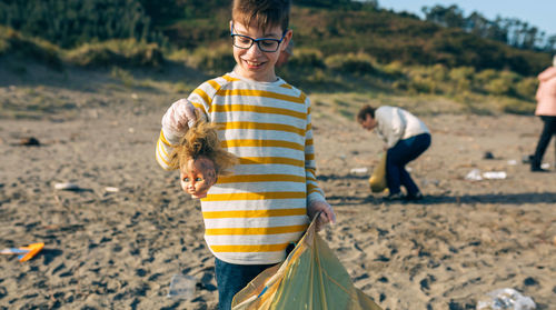 Boy collecting garbage in plastic bag at beach