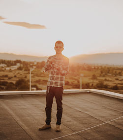 Man standing on terrace against sky during sunset