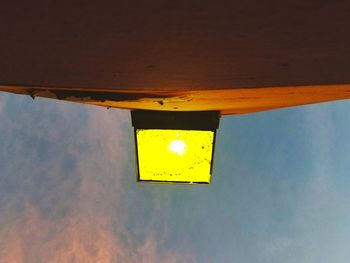 Low angle view of yellow sign against sky