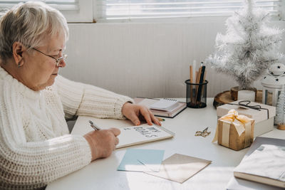 Healthy new years resolutions for older adults. senior mature old woman in white sweater writing