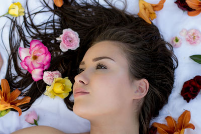 Close-up of thoughtful teenage girl lying amidst flowers on bed