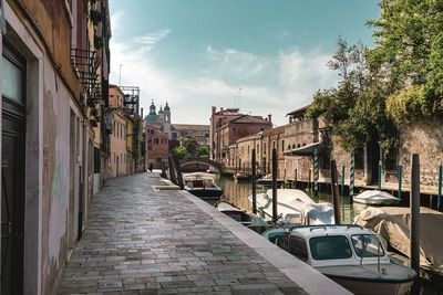 Boats moored in canal amidst buildings in city