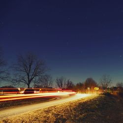 Light trails on road against sky at night