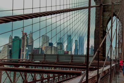 Suspension bridge in city against sky