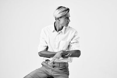 Young man looking away against white background