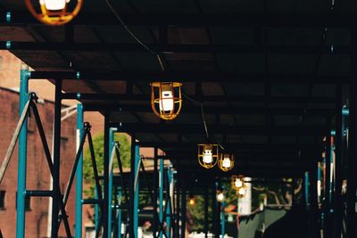 Low angle view of illuminated lighting equipment hanging in covered walkway