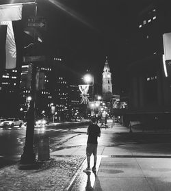 Rear view of woman walking on street at night
