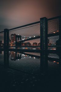 Illuminated city by river against sky at night