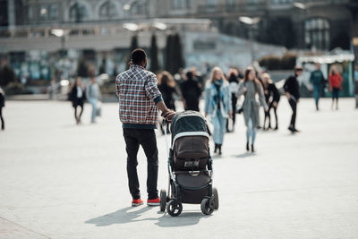 Rear view of people walking on street in city