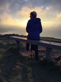 Rear view of man standing against sea during sunset