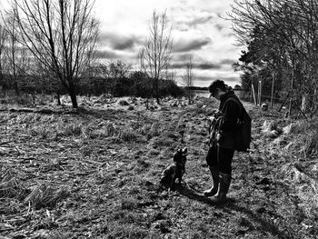 Woman with dog standing on field