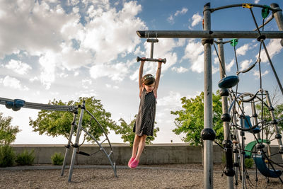 Smiling young girl swings on monkey bars at playground