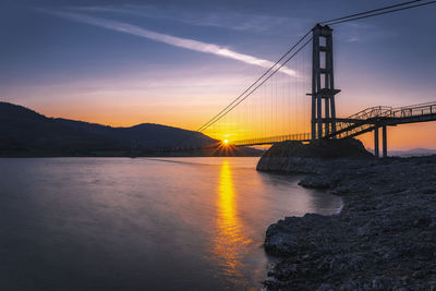 View of suspension bridge over sea during sunset