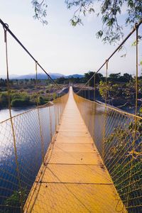 Footbridge over river against sky