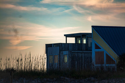 Exterior of house on field against sky during sunset