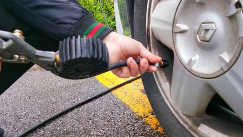 Cropped hand filling air in car tire