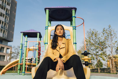 Young woman sitting on slide at playground