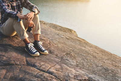 Low section of man on rock by lake 