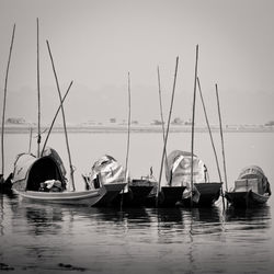 Sailboats moored at harbor against sky