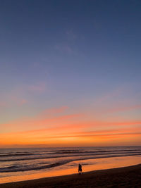 Silhouette person on beach against sky during sunset