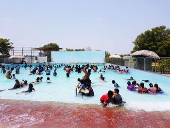 People in swimming pool against clear sky