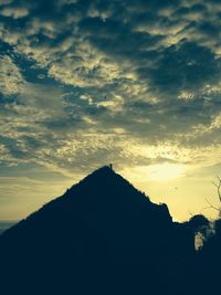 Scenic view of mountains against cloudy sky at sunset