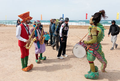 People playing on beach against sky