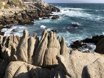 Scenic view of rocks on beach against sky