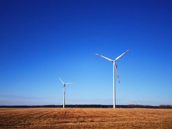 Windmill on field against clear blue sky