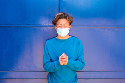 Portrait of a person standing against blue wall