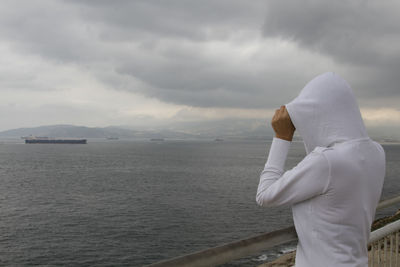 Woman standing by railing against sea and sky