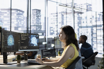 Side view of young woman using mobile phone in office