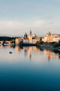 Buildings by the vltava river against sky, prague