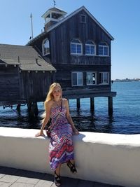 Portrait of woman standing by house against clear sky