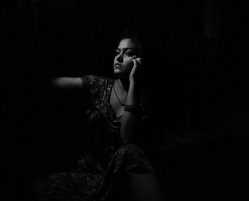 Portrait of young woman sitting in darkroom