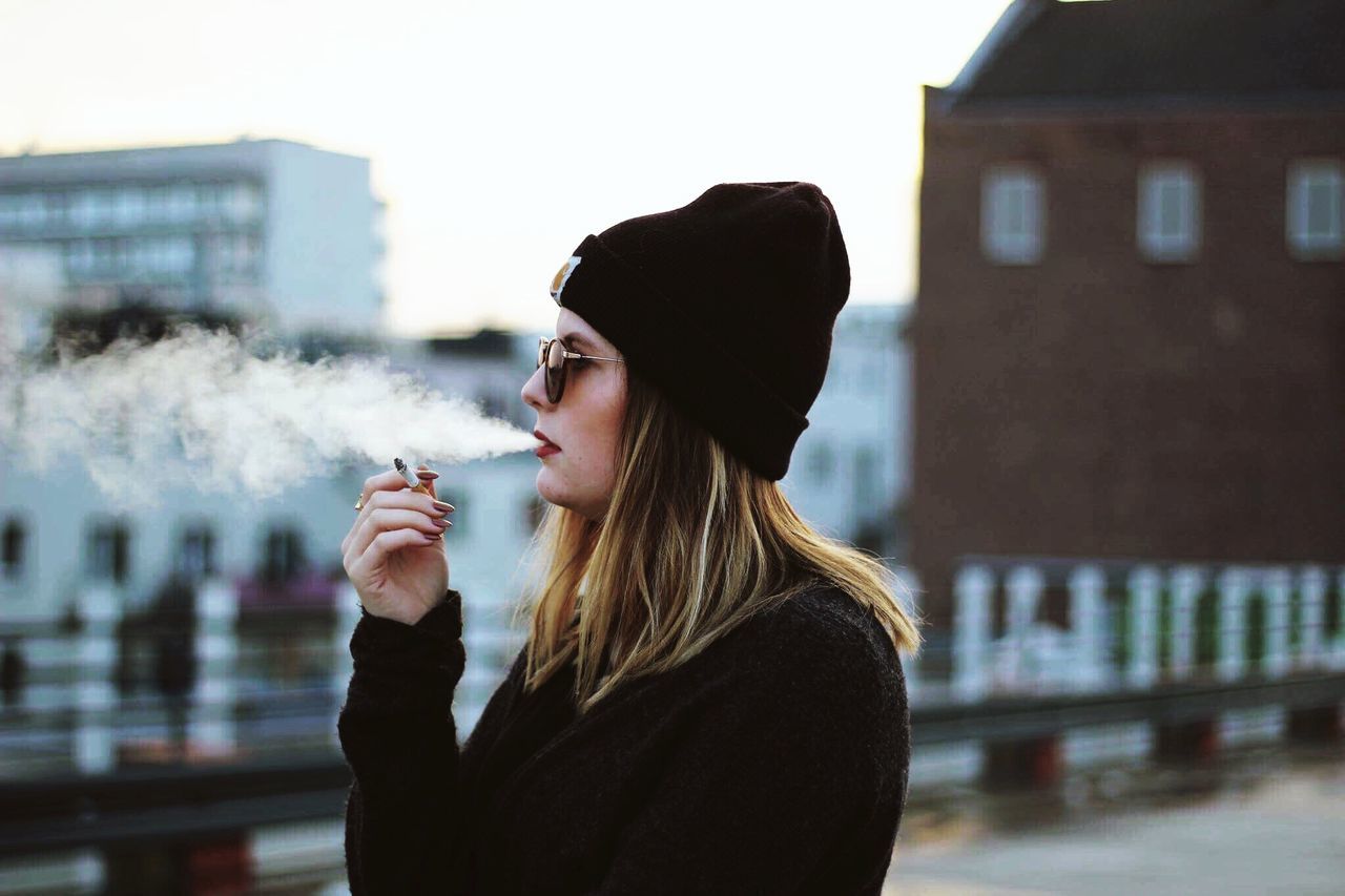 smoking - activity, adults only, smoking issues, one woman only, winter, one person, only women, warm clothing, lifestyles, people, adult, women, smoke - physical structure, outdoors, young adult, day