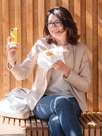 Smiling woman makes selfie with tasty pastry. obsession of posting photos online in social media. 