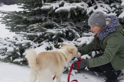 Girl with dog in front of snow covered tree