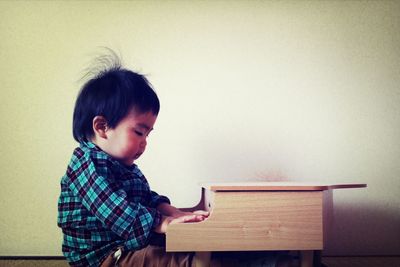 Side view of cute boy against wall at home