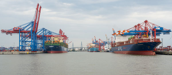 Cranes at commercial dock against sky