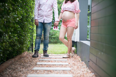Low section of couple standing on footpath while holding hands