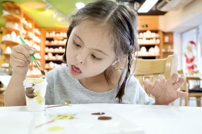 Cute girl painting disposable cup on table