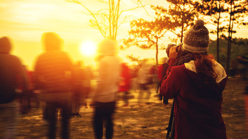 Rear view of people walking on street during sunset