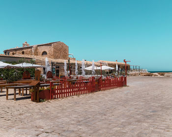 Exterior of building by sea against clear blue sky