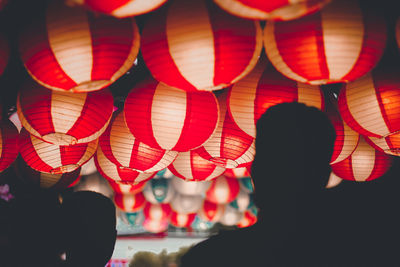 Rear view of silhouette people by illuminated lanterns hanging at night