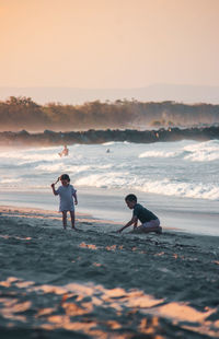 People on beach against sky during sunset