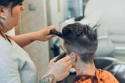 Woman cutting man hair in salon