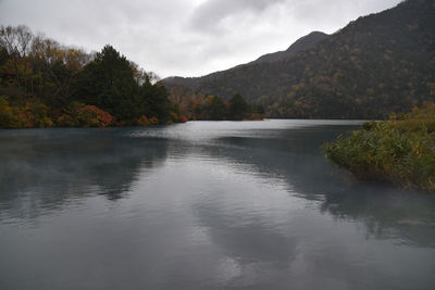 Scenic view of lake by mountains against sky